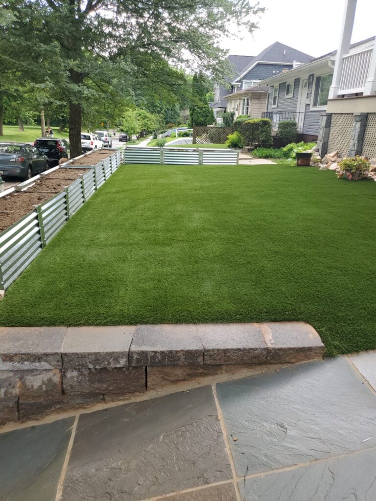 Artificial turf lawn beside raised garden beds and stone hardscaping