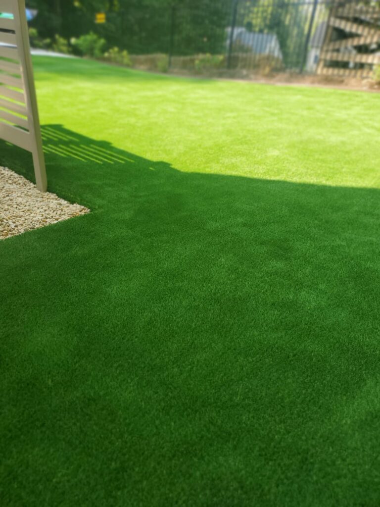 Finished artificial turf lawn surrounding an outdoor structure in a residential backyard