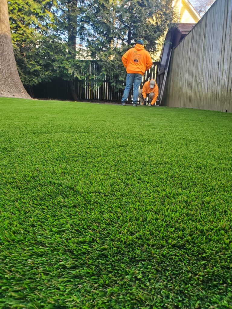 Orange Landscaping crew installing artificial turf in a residential backyard