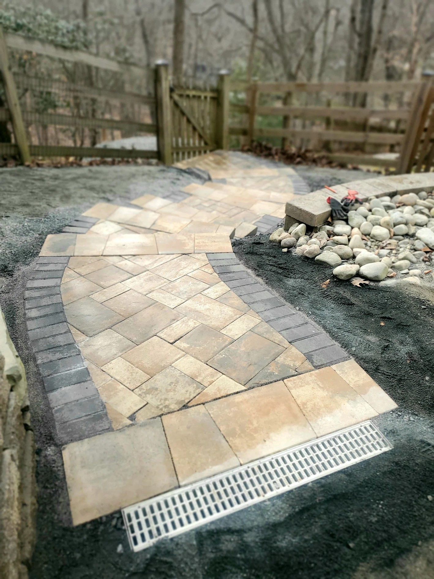 Curved paver walkway with channel drain and decorative stone