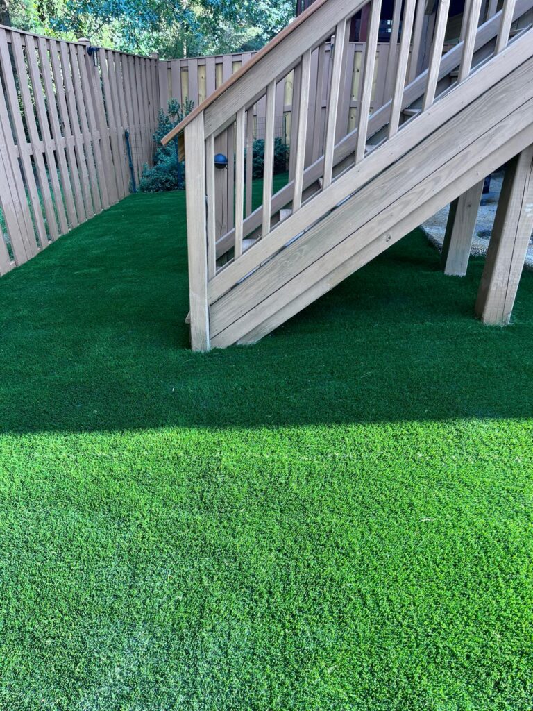 Artificial turf installed around and beneath a raised wooden deck in a Falls Church backyard