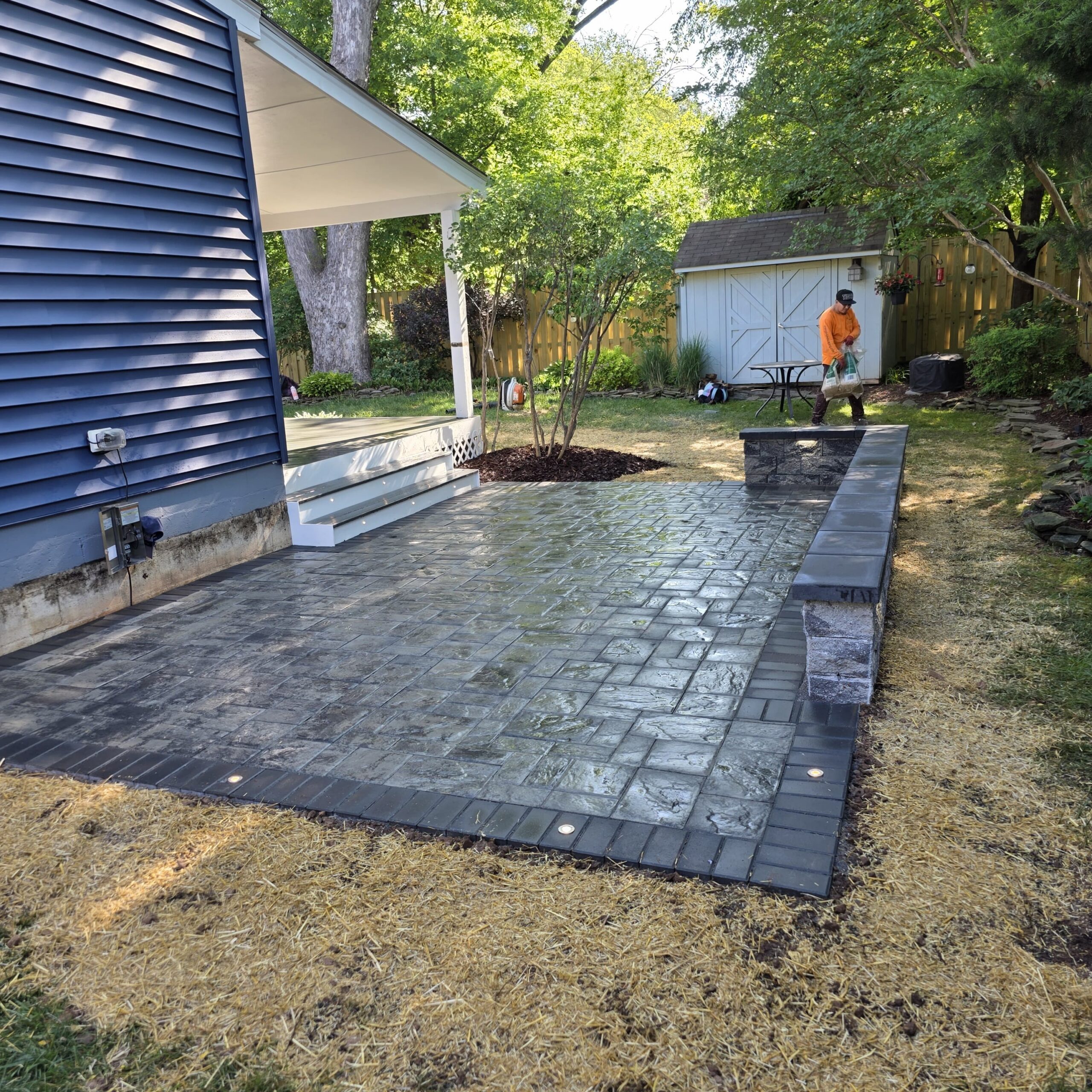 Paver patio with built-in lighting and a low retaining wall in a Manassas backyard